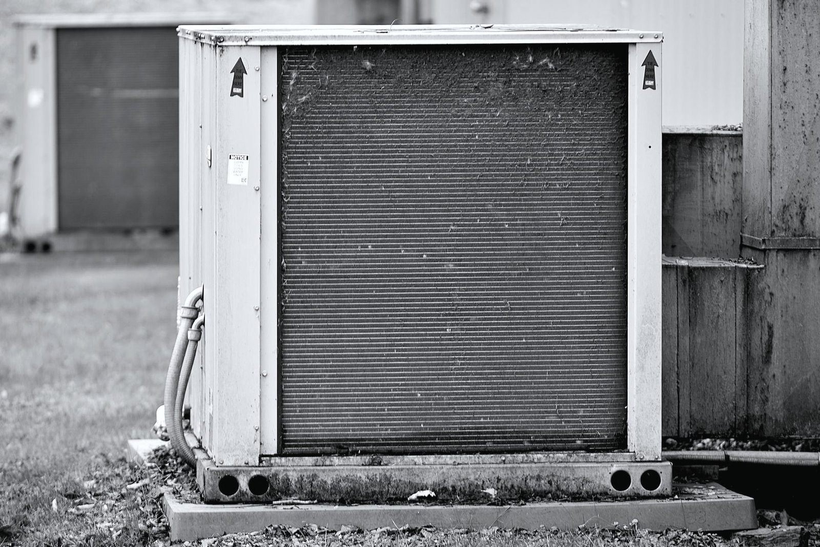 An outdoor air conditioning condenser standing on a pad beside a building